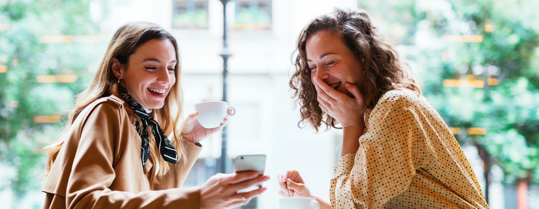 a couple of women sitting at a table and laughing