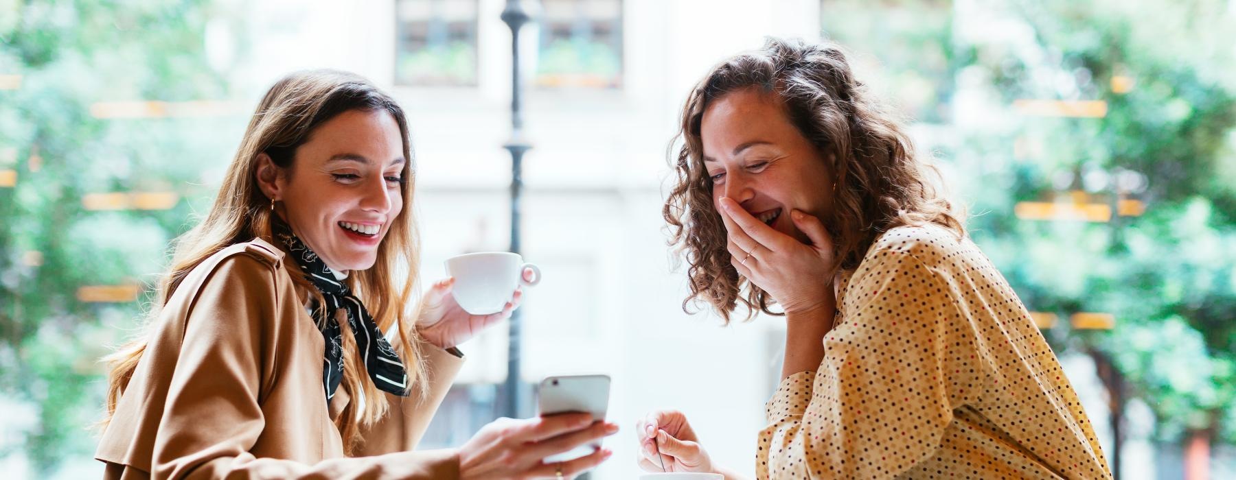 a couple of women sitting at a table and laughing